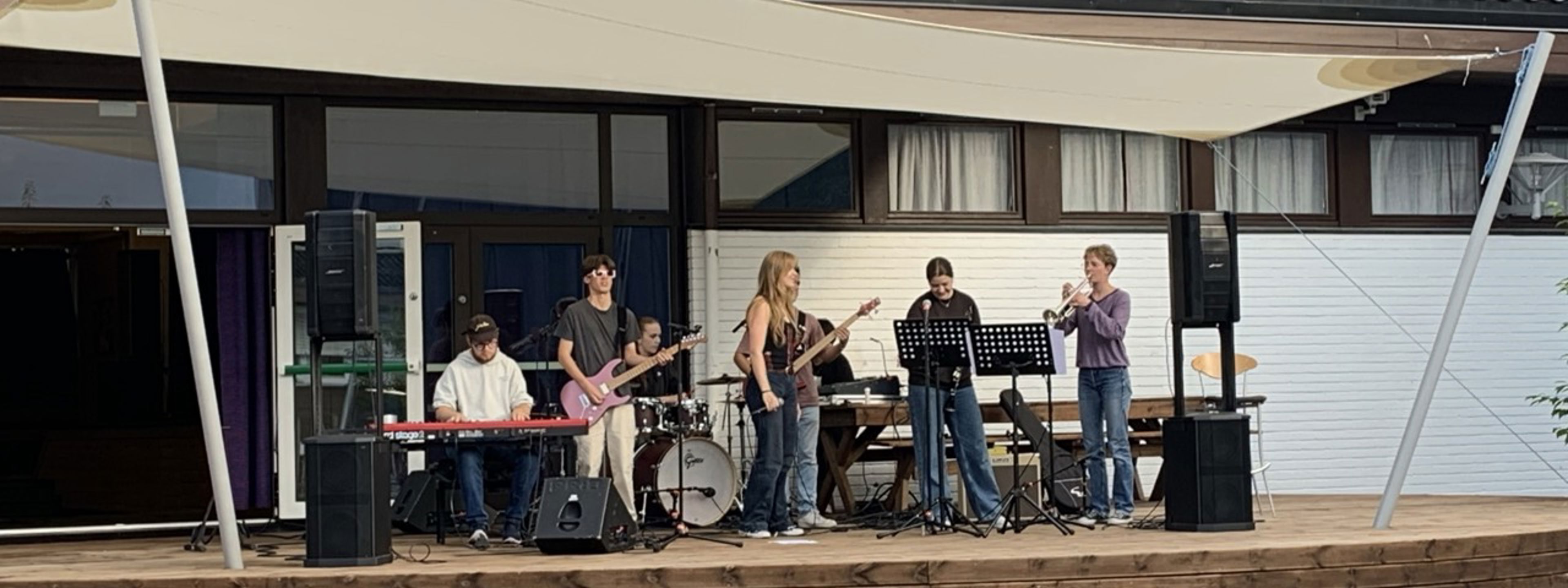 Elevar med musikkinstrument held konsert på scena ved skuleplassen.