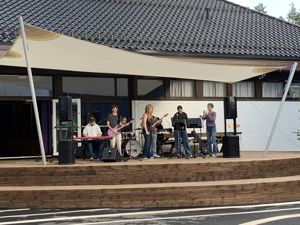Elevar med musikkinstrument held konsert på scena ved skuleplassen.