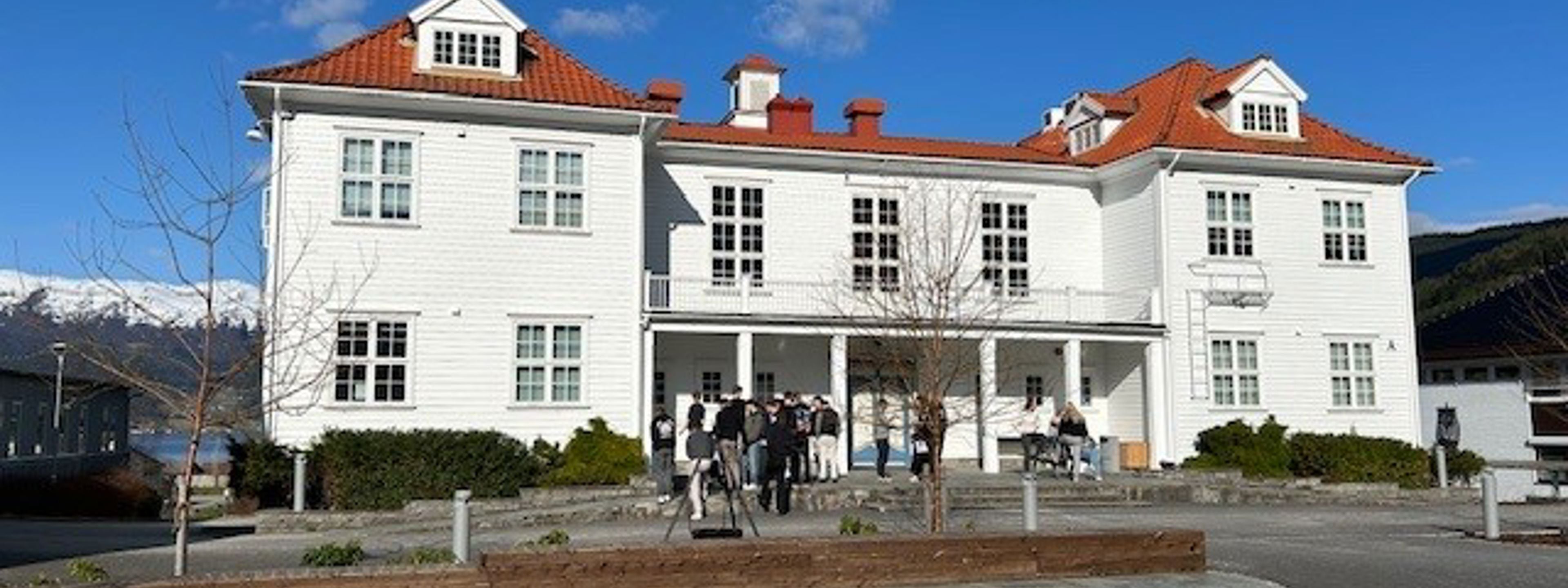 Kvitt trebygg med rødt tak med knall blå himmel i bakgrunnen.
