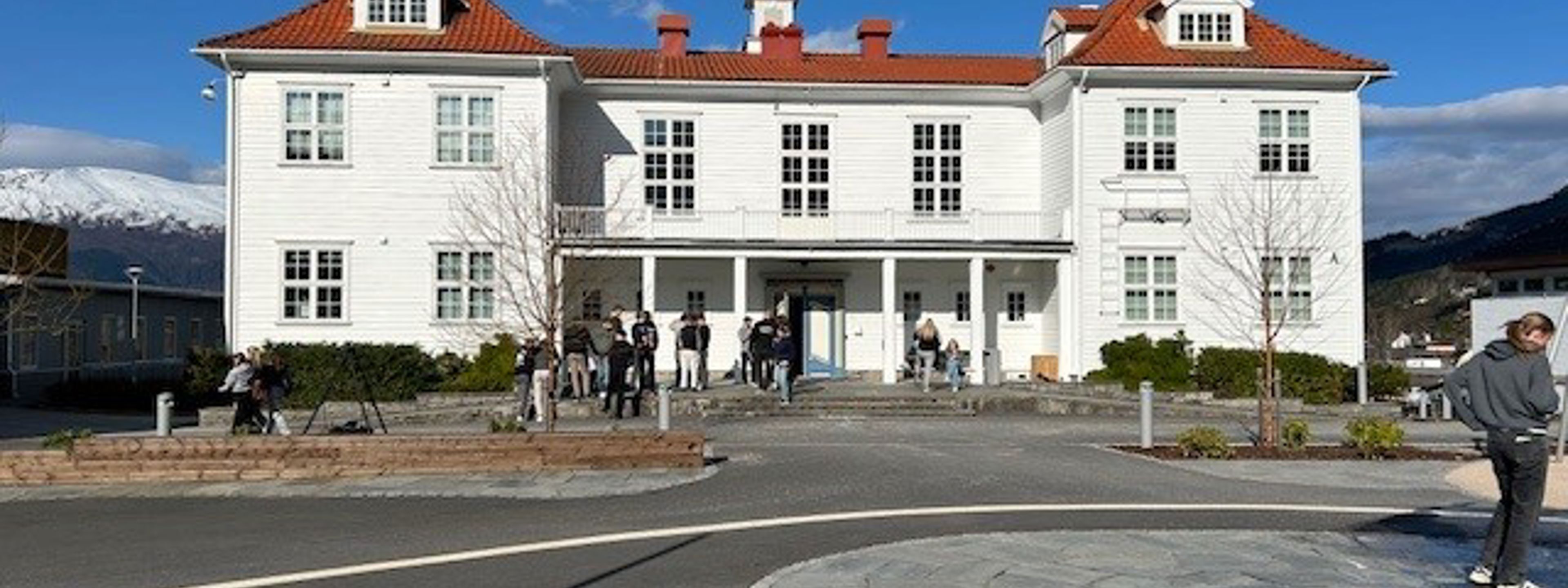 Gamlebygget ved Firda vgs, kvit trebygning med rødt tak, skuleplassen i front.