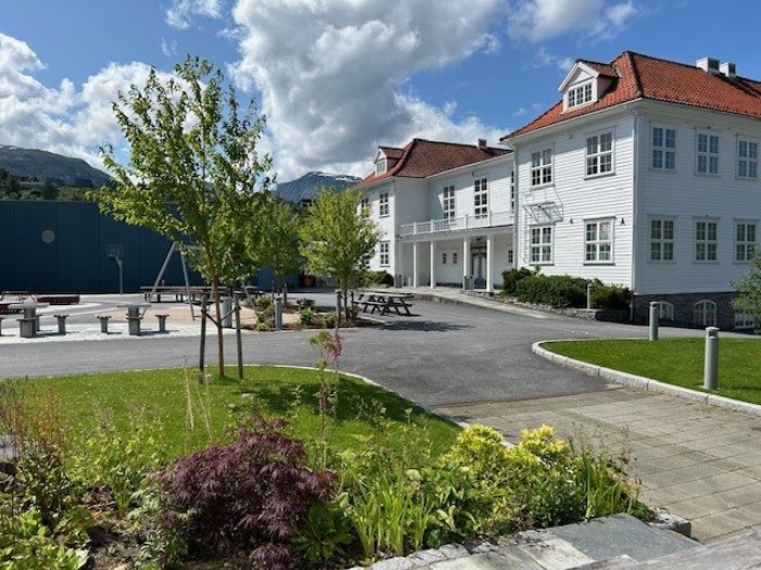 Gamlebygget på Firda vgs med skuleplassen og grøntområde i framgrunnen
