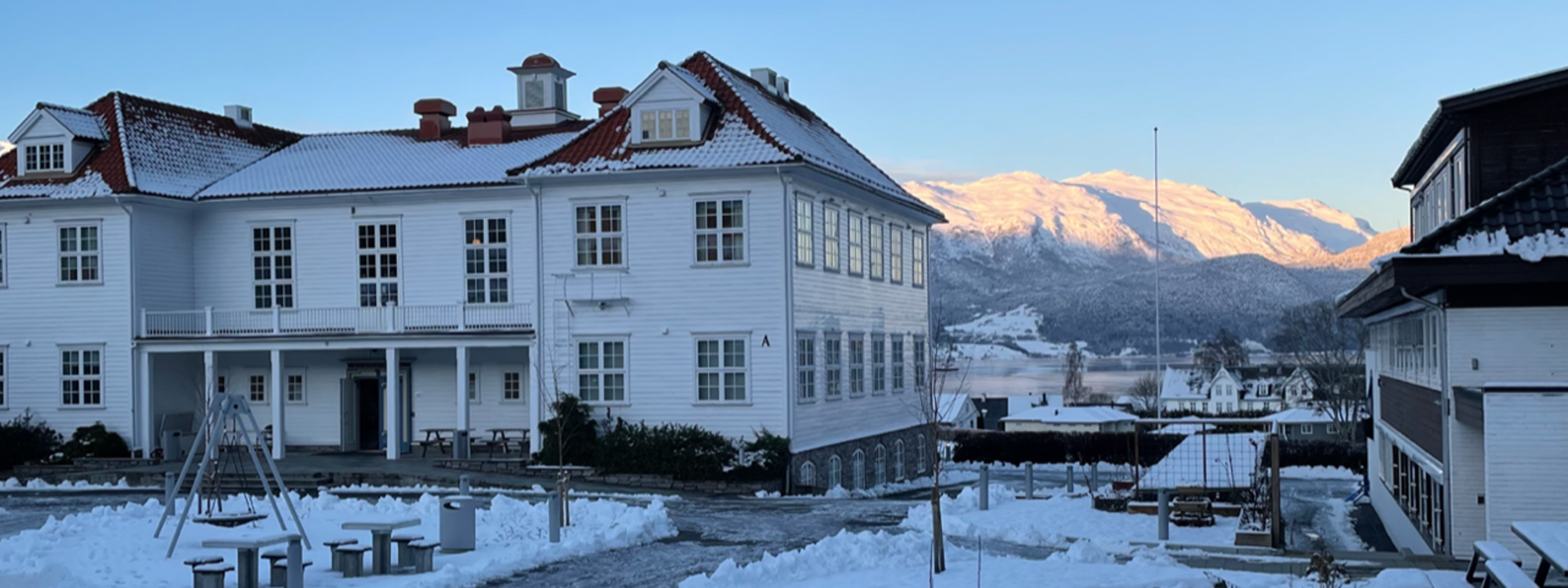 Vinterbilde av hovudbygget og skuleplassen ved Firda vgs